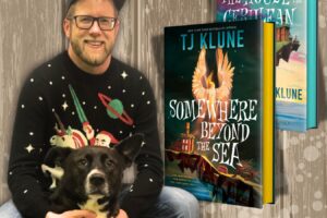 author sitting with his dog and next to cover sof his book