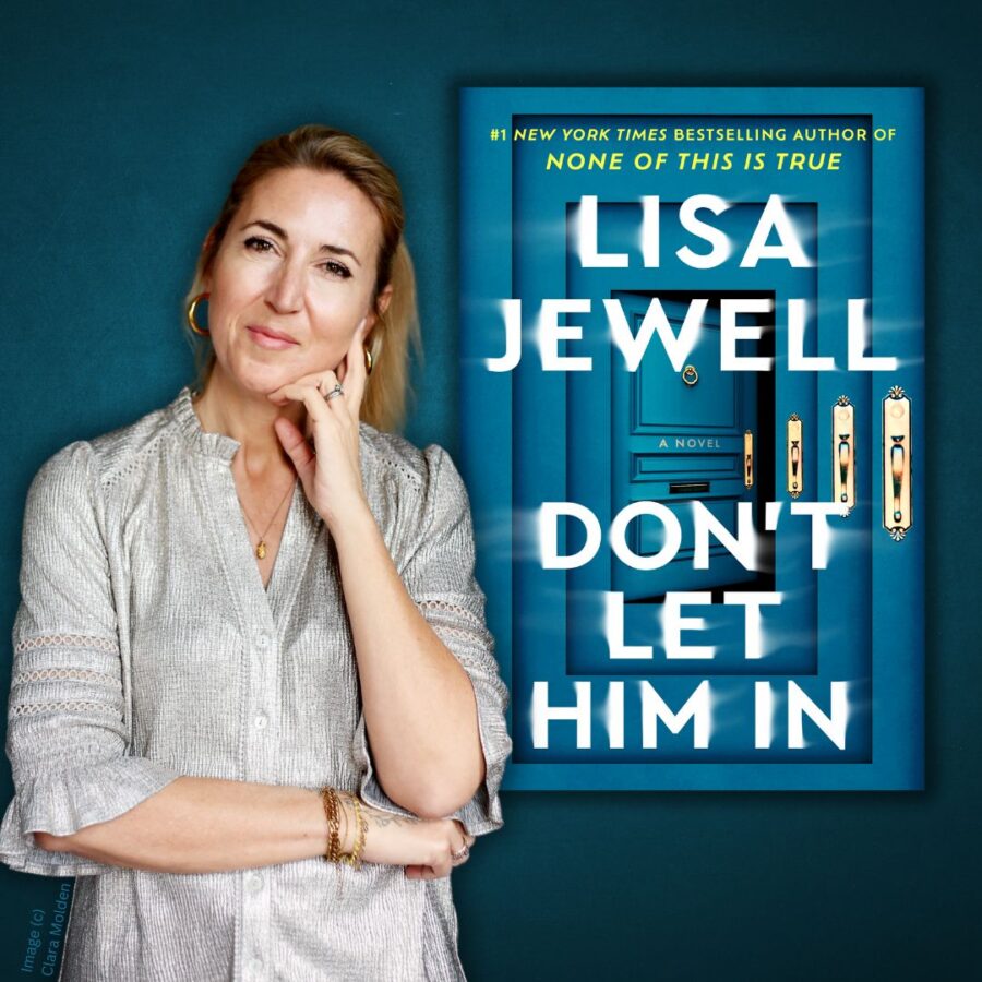 woman standing with hand to chin in front of a larger cover of her book